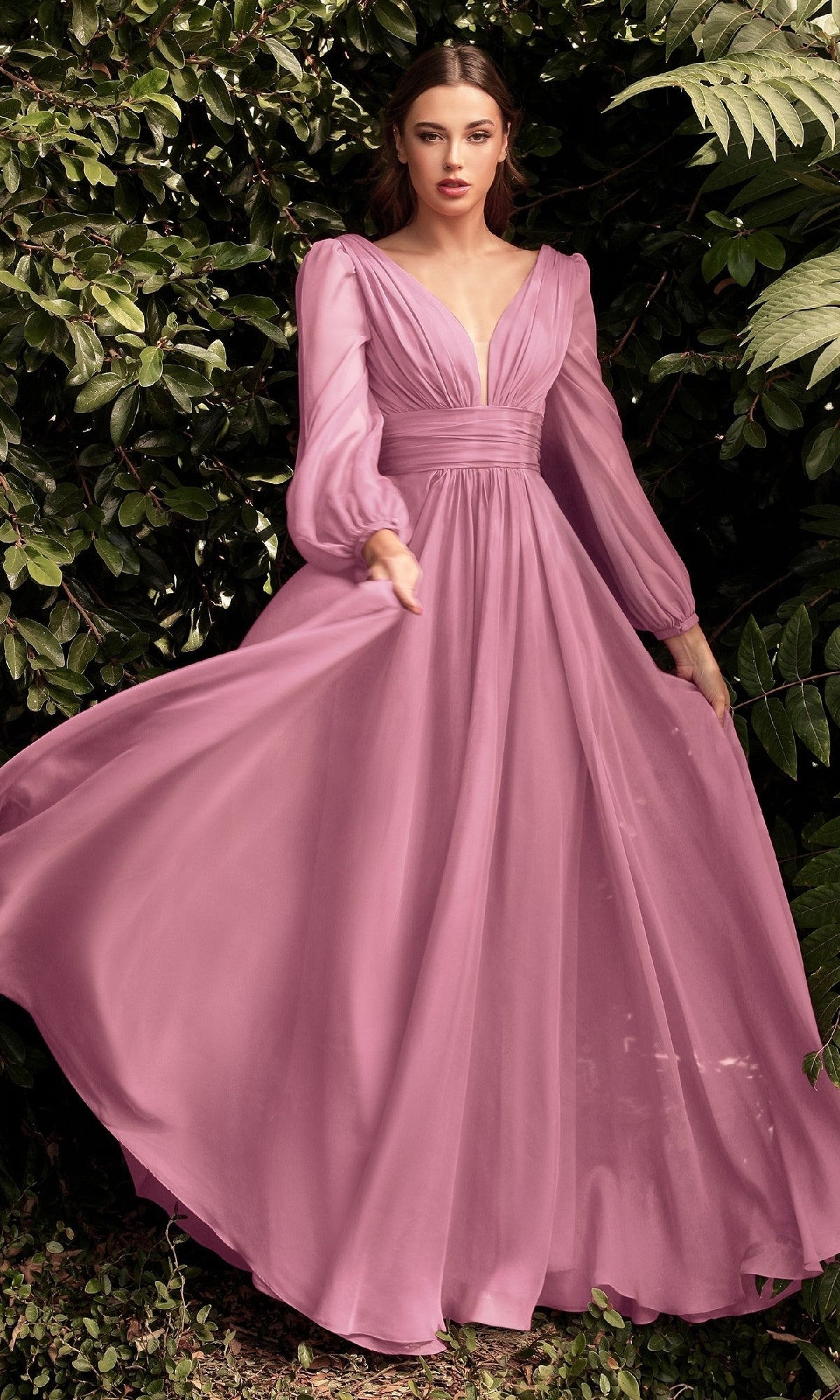 A woman stands outdoors before green foliage, wearing the Ladivine CD0192— a long sleeve flowy mauve prom dress with a deep V-neck and gathered waist—delivering elegant style for under $100.